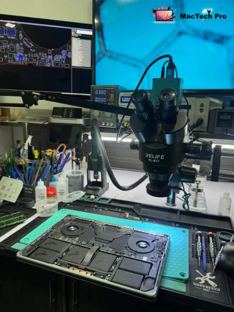 Dan inspecting an M2 MacBook logic board under the microscope for micro-cracks and corrosion — MacTech Pro Dubai Marina